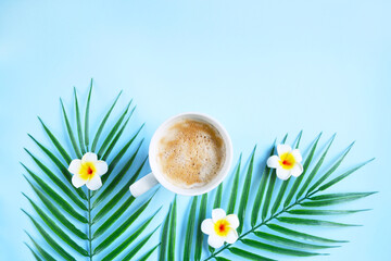 Milk coffee with plumeria flowers and palm leaves on blue. Cozy vocational morning. Coffee break. Relaxing atmosphere. Eco life. Summer style. Hotel room service. Exotic countries.