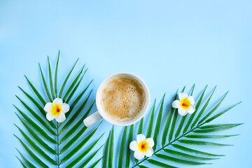 Milk coffee with plumeria flowers and palm leaves on blue. Cozy vocational morning. Coffee break. Relaxing atmosphere. Eco life. Summer style. Hotel room service. Exotic countries.