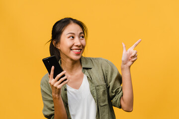 Portrait of young Asian lady using mobile phone with cheerful expression, show something amazing at...