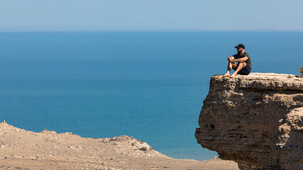 A man looking out across the landscape fropm a cliff edge. Deep in thought, with the sea and rocks...