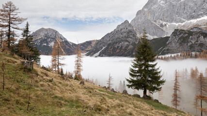 Fog slowly drifting through a valley surrounded by Mountains in Autumn.