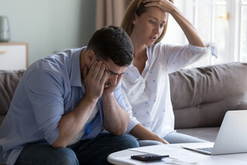 Stressed spouses manage family finances, analyze expenses, check savings and budget, looks disappointed due to mortgage arrears, unpaid utility bills, debt notice. Lack of money, high utility concept - obrazy, fototapety, plakaty