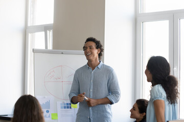 Group of young diverse staff member take part in corporate training led by Hispanic business trainer, makes presentation on flip chart. Seminar event, professional workshop activity, coaching concept