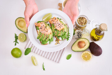 Freshly made Avocado, salmon and cream cheese toasts on a white ceramic plate
