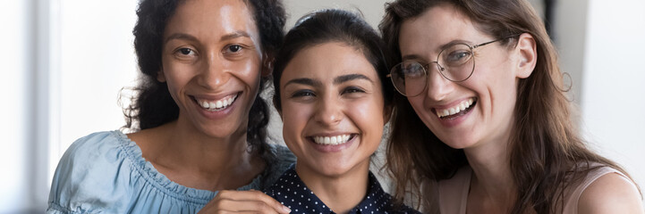 Horizontal photo three laughing multiracial women cropped close up portrait. Faces of attractive African, Indian, Caucasian girlfriends smile look at camera. Amity, friendship, racial equality concept
