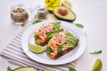 Freshly made Avocado, salmon and cream cheese toasts on a white ceramic plate