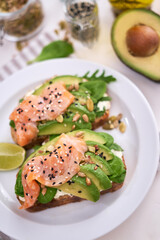 Freshly made Avocado, salmon and cream cheese toasts on a white ceramic plate