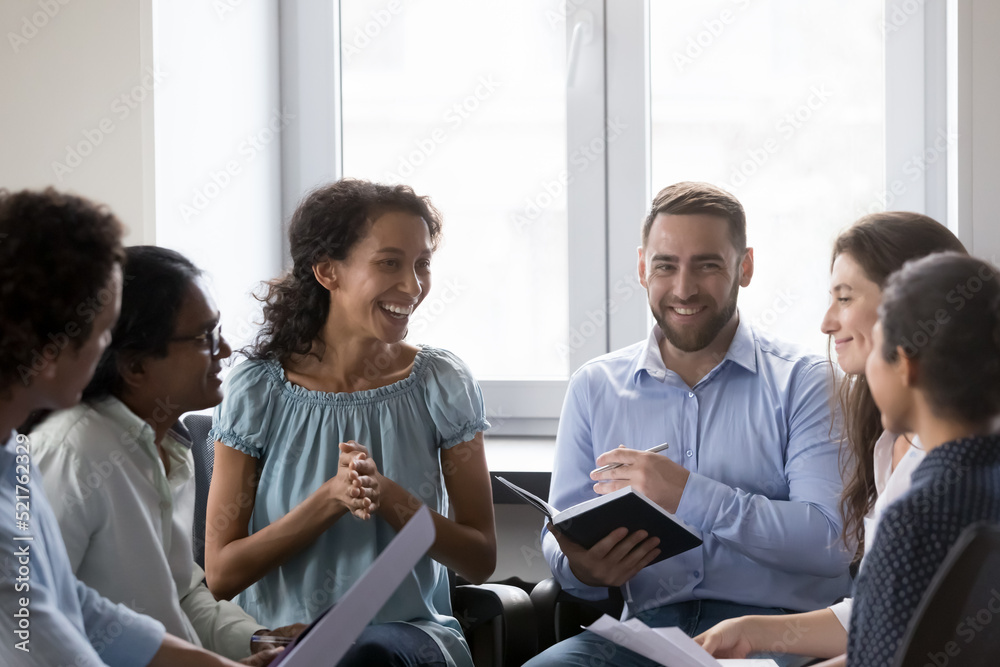 Wall mural smiling multiracial colleagues have fun take part in educational motivational training at workplace.