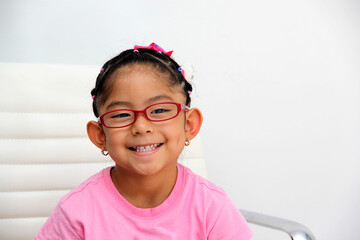 Brunette Latin girl shows her red glasses to see better because she has myopia and astigmatism
