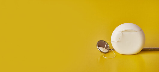 Dental mirror and dental floss on a yellow background. Dental care.