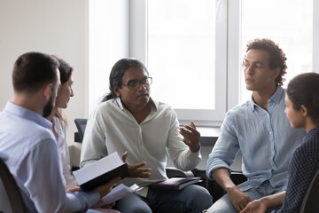 Employees discuss business ideas at office briefing, Indian male team leader or coach give...