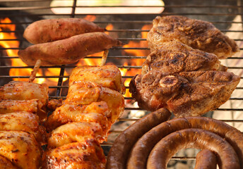 Braai meat including boerewors sausage, lamb chops and chicken kebabs on the grill