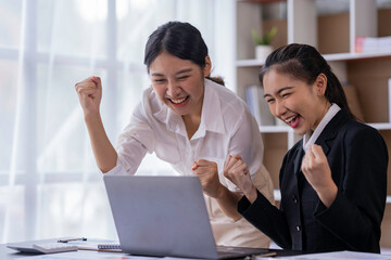 Team work process Two women are immensely rejoicing, Yes, succeeding with laptops in an open...