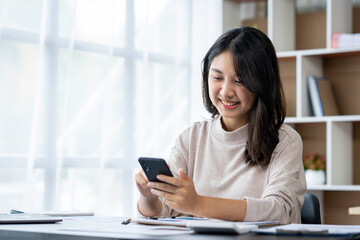 Asian businesswomen use laptops and smartphones in an open space office. Business concept. Data analysis, roadmap, marketing, accounting, auditing.