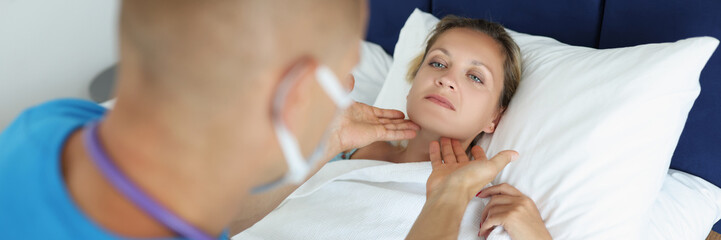 Obraz na płótnie Canvas Sick woman lies in bed doctor man checks lymph nodes
