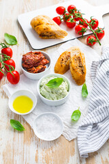 Avocado spread and sun dried tomatoes with olive oil as antipasto and baguette