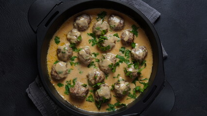 Rustic homemade Swedish meatballs in a pan with cream sauce and parsley
