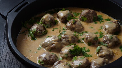 Rustic homemade Swedish meatballs in a pan with cream sauce and parsley