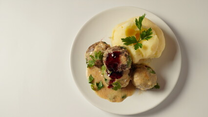 A plate of Swedish meatballs with mashed potatoes, traditional creamy gravy, and lingonberry. - obrazy, fototapety, plakaty