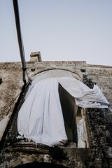 Low angle view of white heavy curtains hanging on the arched window of old castle