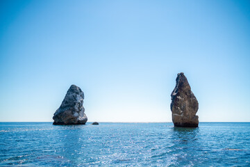 Two rocks stick out of the water in the middle of the turquoise sea. Scenic ocean views. High...