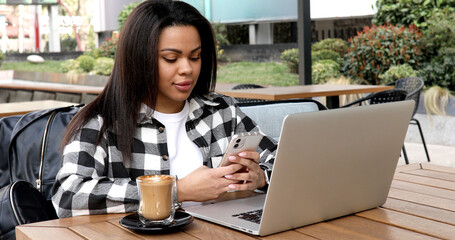 Young african woman using laptop outdoors.