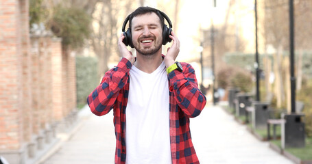 Modern young smiling man enjoying music outdoor.