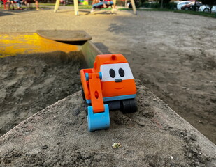 Bright plastic children's toy truck shot in vertical format. Excavator is essential toy when kids play in the sandbox. A little helper in digging