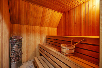 Wooden orange walls and benches in modern sauna with heater