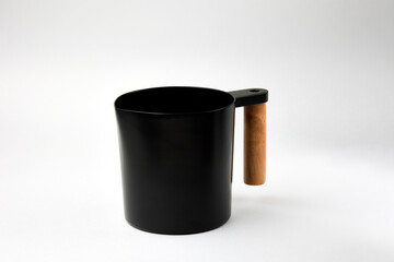 Black jar with wooden handle stands on white background
