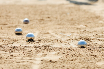 Four silver balls lie on sand of sea beach reflecting sky