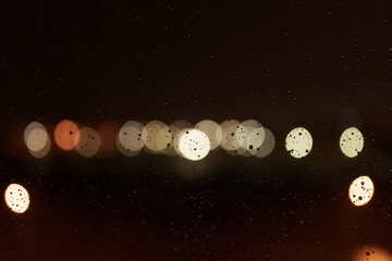 Closeup of water drops on a window with city lights on background
