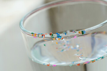  Microplastics or tiny plastic particles in a glass of water.Drinking water contaminated with...