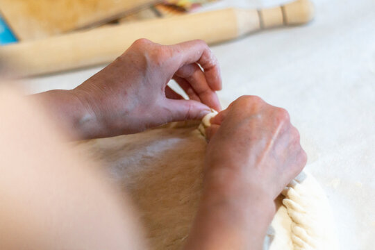 Women's hands sculpt from the dough a large pirok with potatoes and msyaom. Home national cuisine