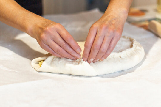 Women's hands sculpt from the dough a large pirok with potatoes and msyaom. Home national cuisine