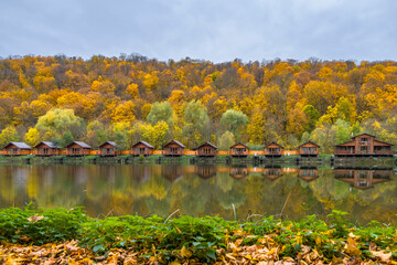 Cottages on lake shore in autumn forest. Country guest houses