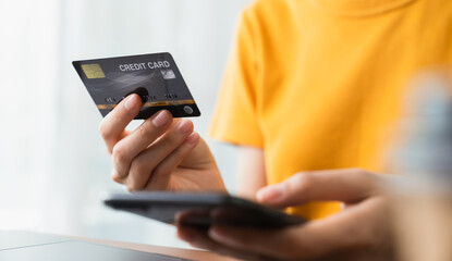 Woman hand holding credit card and using smartphone for paying products online via the Internet