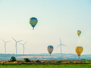 Obraz premium Globos aerostáticos volando sobre una instalación eólica en Cadiz