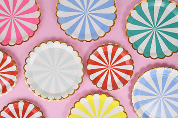 Colorful striped paper party plates on pink background