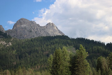 Fototapeta premium Coravara, Italy-July 16, 2022: The italian Dolomites behind the small village of Corvara in summer days with beaitiful blue sky in the background. Green nature in the middle of the rocks.