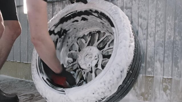 Car washer accurately washes wheel disk of automobile with sponge in carwash