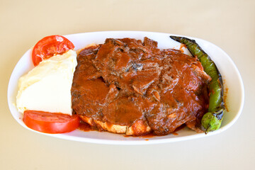 Turkish and Arabic Traditional Ramadan doner kebab with tasty tomato sauce and rice or turkish pilav in white plate on wood table background. ( , Iskender, ekmek arasi pilav ustu doner, doner durum )