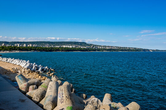 Distant city of Varna as seen from the edge of the port. Wave-breaking stones in the foreground.