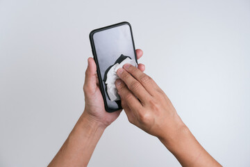 Hand wiping the mobile phone with the alcohol sanitiser wipes  to clean and prevent the spread of bacteria and virus.  Personal hygiene concept. Isolated white background