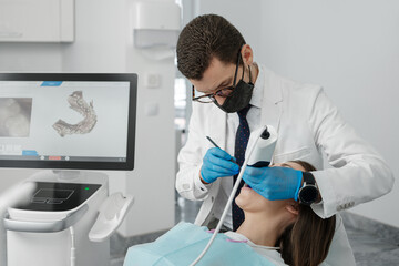 Male orthodontist scaning patient with dental intraoral scanner and controls process on screen. - obrazy, fototapety, plakaty