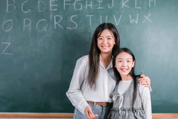 Smiling Asian Teacher woman teaching student in english classroom, Female teacher writing on blackboard, High school and back to school concept.