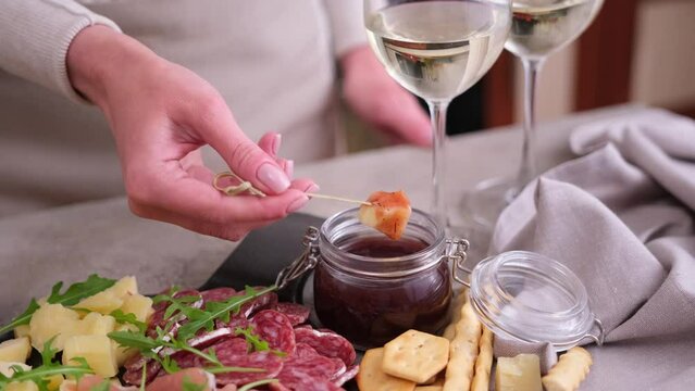 meat and cheese plater at domestic kitchen - woman dips cheese into sauce