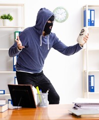 Male thief in balaclava in the office