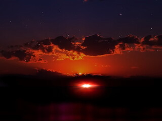 Fototapeta premium night sunset at sea dramatic cloudy sky with gold sunbeams