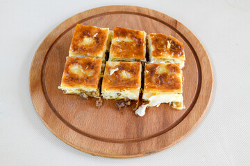 Turkish style meat stuffed filo dough borek served kol boregi. Cheese and minced pie are sliced on a marble background. Turkish name: Kol Boregi, kiymali, peynirli su boregi.
